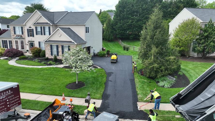 Residential driveway with workers applying asphalt sealcoating