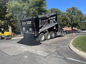 Cedar scaping dumptruck pouring asphalt onto road